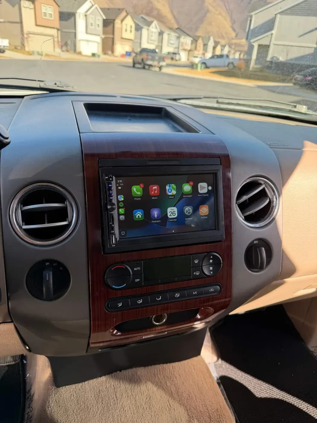 CarPlay touchscreen installed in a wood-trimmed dashboard